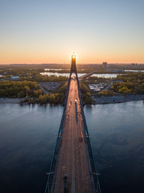 Kiev 'in kuzey köprüsü. Köprü boyunca yükselen güneş ışınları. Güneş pilonun içinden doğuyor. Hava aracı görünümü.