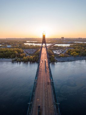 Kiev 'in kuzey köprüsü. Köprü boyunca yükselen güneş ışınları. Güneş pilonun içinden doğuyor. Hava aracı görünümü.
