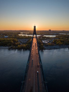 Kiev 'in kuzey köprüsü. Köprü boyunca yükselen güneş ışınları. Güneş pilonun içinden doğuyor. Hava aracı görünümü.