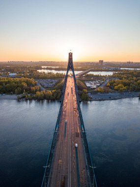 Kiev 'in kuzey köprüsü. Köprü boyunca yükselen güneş ışınları. Güneş pilonun içinden doğuyor. Hava aracı görünümü.