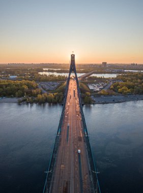 Kiev 'in kuzey köprüsü. Köprü boyunca yükselen güneş ışınları. Güneş pilonun içinden doğuyor. Hava aracı görünümü.