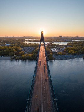 Kiev 'in kuzey köprüsü. Köprü boyunca yükselen güneş ışınları. Güneş pilonun içinden doğuyor. Hava aracı görünümü.
