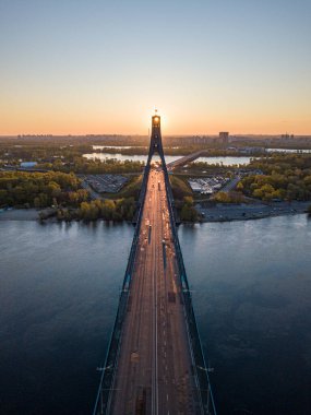 Kiev 'in kuzey köprüsü. Köprü boyunca yükselen güneş ışınları. Güneş pilonun içinden doğuyor. Hava aracı görünümü.