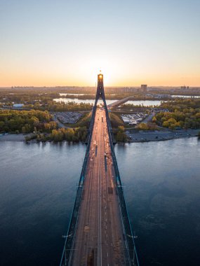 Kiev 'in kuzey köprüsü. Köprü boyunca yükselen güneş ışınları. Güneş pilonun içinden doğuyor. Hava aracı görünümü.