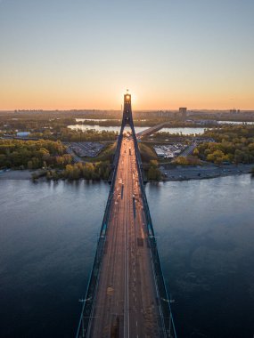 Kiev 'in kuzey köprüsü. Köprü boyunca yükselen güneş ışınları. Güneş pilonun içinden doğuyor. Hava aracı görünümü.