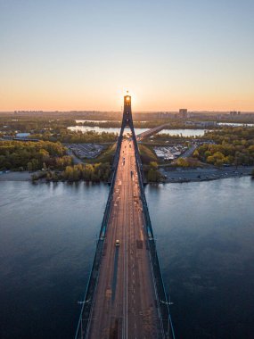 Kiev 'in kuzey köprüsü. Köprü boyunca yükselen güneş ışınları. Güneş pilonun içinden doğuyor. Hava aracı görünümü.