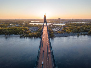 Kiev 'in kuzey köprüsü. Köprü boyunca yükselen güneş ışınları. Güneş pilonun içinden doğuyor. Hava aracı görünümü.