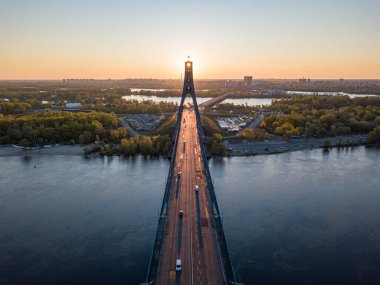 Kiev 'in kuzey köprüsü. Köprü boyunca yükselen güneş ışınları. Güneş pilonun içinden doğuyor. Hava aracı görünümü.
