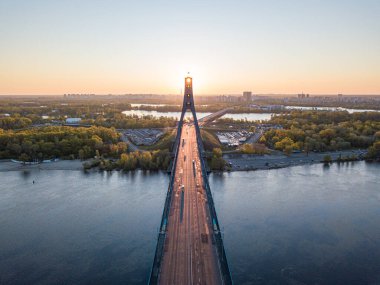 Kiev 'in kuzey köprüsü. Köprü boyunca yükselen güneş ışınları. Güneş pilonun içinden doğuyor. Hava aracı görünümü.