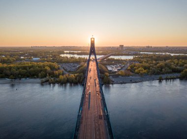 Kiev 'in kuzey köprüsü. Köprü boyunca yükselen güneş ışınları. Güneş pilonun içinden doğuyor. Hava aracı görünümü.