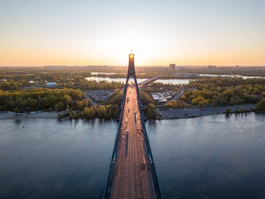 Kiev 'in kuzey köprüsü. Köprü boyunca yükselen güneş ışınları. Güneş pilonun içinden doğuyor. Hava aracı görünümü.