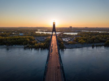 Kiev 'in kuzey köprüsü. Köprü boyunca yükselen güneş ışınları. Güneş pilonun içinden doğuyor. Hava aracı görünümü.