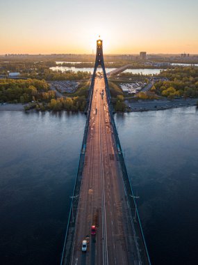 Kiev 'in kuzey köprüsü. Köprü boyunca yükselen güneş ışınları. Güneş pilonun içinden doğuyor. Hava aracı görünümü.