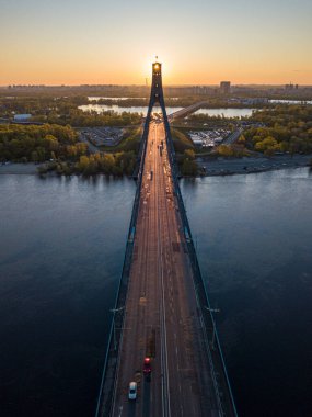 Kiev 'in kuzey köprüsü. Köprü boyunca yükselen güneş ışınları. Güneş pilonun içinden doğuyor. Hava aracı görünümü.