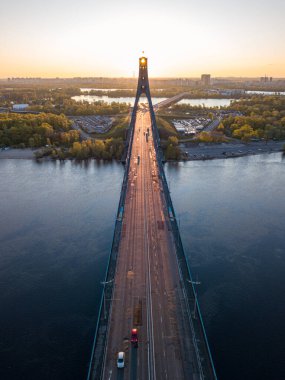 Kiev 'in kuzey köprüsü. Köprü boyunca yükselen güneş ışınları. Güneş pilonun içinden doğuyor. Hava aracı görünümü.
