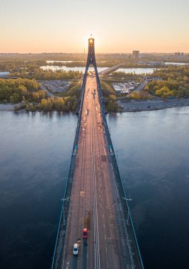 Kiev 'in kuzey köprüsü. Köprü boyunca yükselen güneş ışınları. Güneş pilonun içinden doğuyor. Hava aracı görünümü.