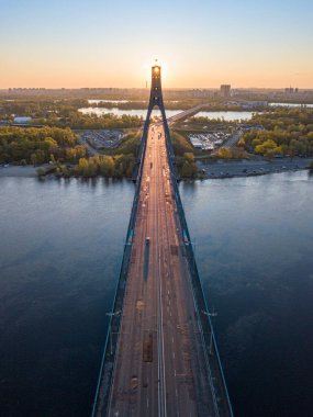 Kiev 'in kuzey köprüsü. Köprü boyunca yükselen güneş ışınları. Güneş pilonun içinden doğuyor. Hava aracı görünümü.