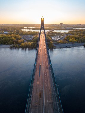 Kiev 'in kuzey köprüsü. Köprü boyunca yükselen güneş ışınları. Güneş pilonun içinden doğuyor. Hava aracı görünümü.