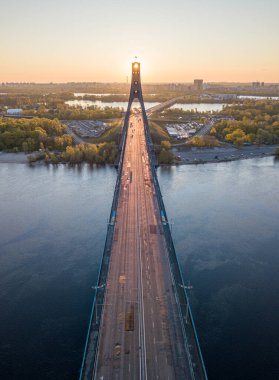 Kiev 'in kuzey köprüsü. Köprü boyunca yükselen güneş ışınları. Güneş pilonun içinden doğuyor. Hava aracı görünümü.