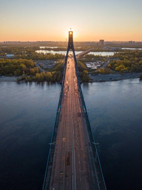 Kiev 'in kuzey köprüsü. Köprü boyunca yükselen güneş ışınları. Güneş pilonun içinden doğuyor. Hava aracı görünümü.