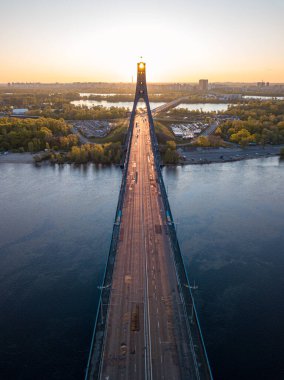 Kiev 'in kuzey köprüsü. Köprü boyunca yükselen güneş ışınları. Güneş pilonun içinden doğuyor. Hava aracı görünümü.