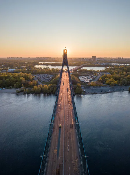 Kiev 'in kuzey köprüsü. Köprü boyunca yükselen güneş ışınları. Güneş pilonun içinden doğuyor. Hava aracı görünümü.