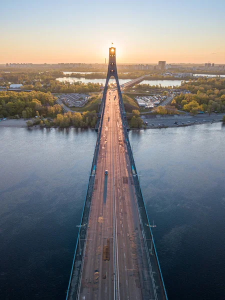 Kiev 'in kuzey köprüsü. Köprü boyunca yükselen güneş ışınları. Güneş pilonun içinden doğuyor. Hava aracı görünümü.