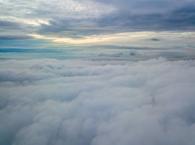 Bulutların üzerinde havadan yüksek uçuş. Yükselen güneşin ışınları bulutları delip geçer..