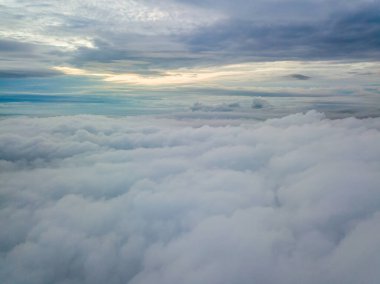 Bulutların üzerinde havadan yüksek uçuş. Yükselen güneşin ışınları bulutları delip geçer..
