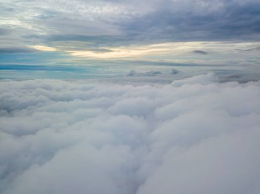 Bulutların üzerinde havadan yüksek uçuş. Yükselen güneşin ışınları bulutları delip geçer..
