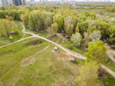 Baharda yeşil çalıların arasındaki toprak yol. Hava aracı görünümü.