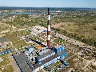 Şehrin varoşlarındaki bir elektrik santralinin yüksek bacası. Arka planda yeşil bahar bozkırları var. Hava aracı görünümü.