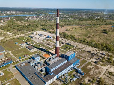 Şehrin varoşlarındaki bir elektrik santralinin yüksek bacası. Arka planda yeşil bahar bozkırları var. Hava aracı görünümü.