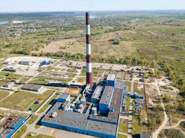 Şehrin varoşlarındaki bir elektrik santralinin yüksek bacası. Arka planda yeşil bahar bozkırları var. Hava aracı görünümü.