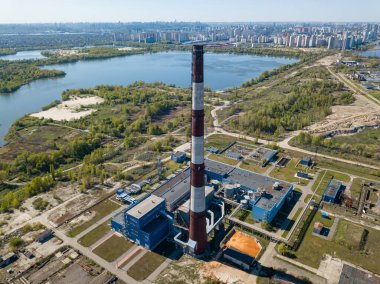 Şehrin varoşlarındaki bir elektrik santralinin yüksek bacası. Arka planda yeşil bahar bozkırları var. Hava aracı görünümü.