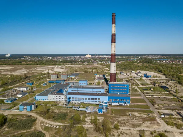 Şehrin varoşlarındaki bir elektrik santralinin yüksek bacası. Arka planda yeşil bahar bozkırları var. Hava aracı görünümü.