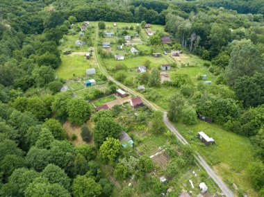 Yeşil yaprak döken ormanların arasında alçak bir yerleşim yeri. Hava aracı görünümü.