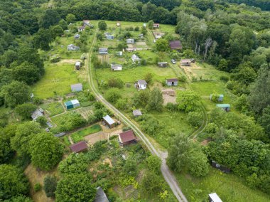 Yeşil yaprak döken ormanların arasında alçak bir yerleşim yeri. Hava aracı görünümü.