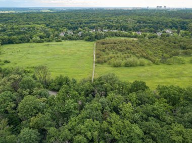 Yeşil yaprak döken ormanların arasında alçak bir yerleşim yeri. Hava aracı görünümü.