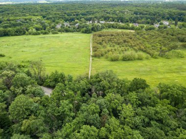 Yeşil yaprak döken ormanların arasında alçak bir yerleşim yeri. Hava aracı görünümü.