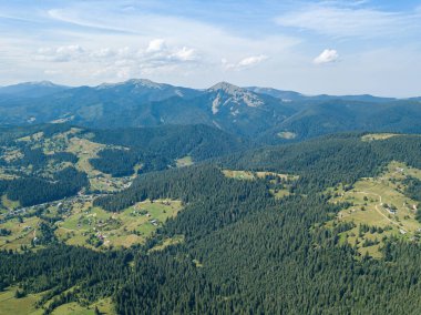 Güneşli bir yaz sabahında Ukrayna Karpatlarının yeşil dağları. Dağ yamaçlarında kozalaklı ağaçlar ve yeşil çimenler. Hava aracı görünümü.