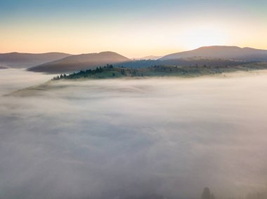 Sis şafakta dağların üzerine yayılır. Güneş ufuktan doğuyor. Sabah Ukraynalı Karpatlar. Hava aracı görünümü.