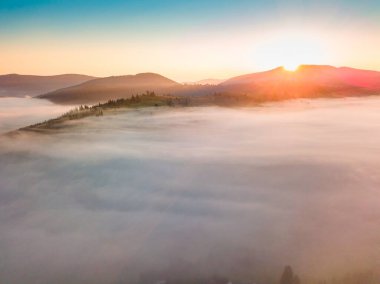 Sis şafakta dağların üzerine yayılır. Güneş ufuktan doğuyor. Sabah Ukraynalı Karpatlar. Hava aracı görünümü.