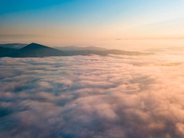 Dağlardaki sislerin üzerinden yüksek uçuş. Sabah Ukraynalı Karpatlar. Hava aracı görünümü.