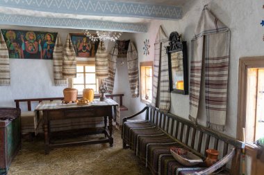 Geleneksel köy odası içi ahşap mobilyalar ve dokuma kumaşlarla dolu.