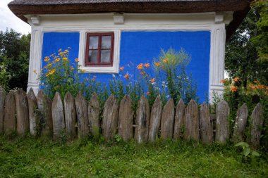Mavi duvarı ve ahşap çitleri olan geleneksel bir ev.