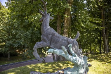 Bereketli yeşil bir parkta bronz geyik heykeli