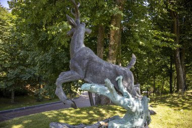 Bronz geyik heykeli parkta dalların üzerinden atlıyor
