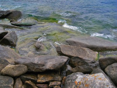 Deniz Baykal doğası. Kıyı kayaların üzerinde inişli çıkışlı dalgalar