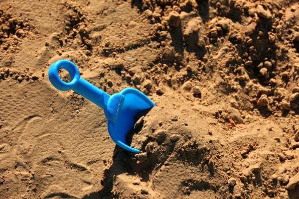 Espátula azul das crianças, presa na areia — Fotografia de Stock